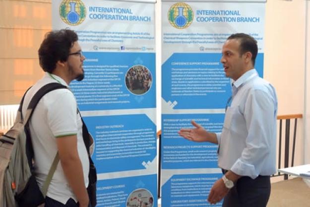 OPCW staff member Farid Tata (right) explains the work of the organisation to a conference attendee.